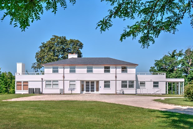 Large white historical home with lots of windows.