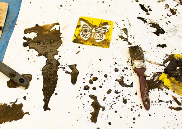 Wet mud brushed over cutout templates to create art.