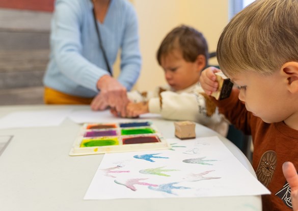 Instructor helping young children learn how to paint.