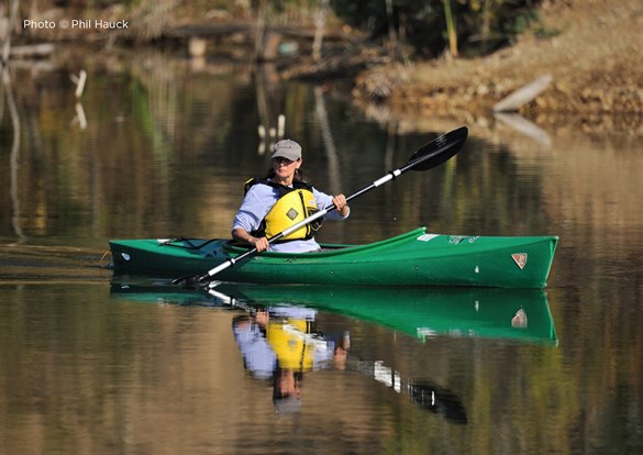 Female senior paddling a green kayak on the Des Plaines River.