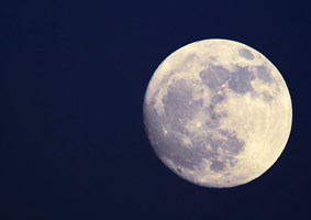 Bright full moon setting in the dark blue sky