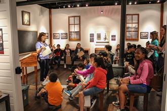 Instructor teaching to a class of students on the subject Early Settlers.