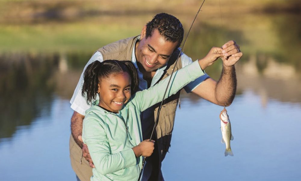 Father and daughter holding up a small fish.