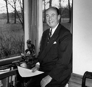 Photo of Adlai E. Stevenson sitting on his desk in his office