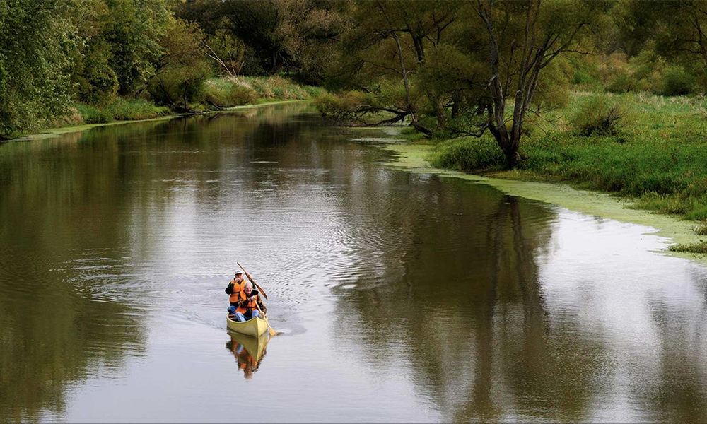 Two men canoeing down a winding river.