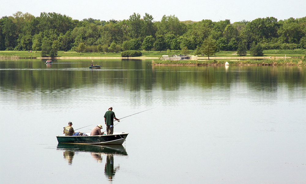 Three men fishing in the middle of the lake from a boat.