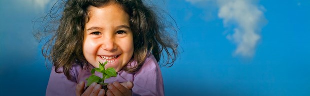 Cute little girl holding a small plant in her hands celebrating Earth Week