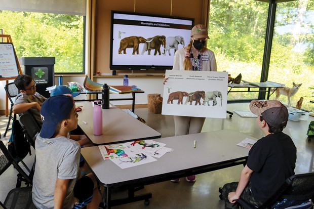 Instructor teaching a group of students about dinosaurs in a classroom.