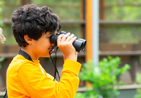School students outdoors looking through binoculars
