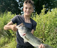 Young boy holding a largemouth bass he just caught.