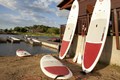 Standup paddle boards lined up along side a building at the beach.