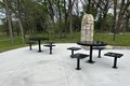 Concrete patio with black metal seats and tables.