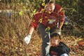 Woman leaning over a young in the woods cutting buckthorn.
