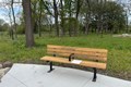 Wooden bench with black metal legs in a park.