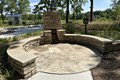 Circular stone patio with stone retaining wall, fireplace.