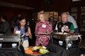 Several people filling plates of food at a buffet table.