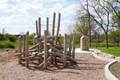 Kids climbing structure made of logs in a park.