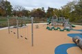 Playground set and swings in a large open playground.