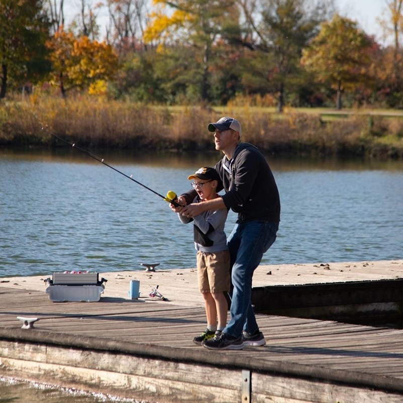 Father and 2 children fishing from a pier.