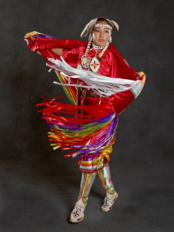 Woman is brightly color Native American outfit.