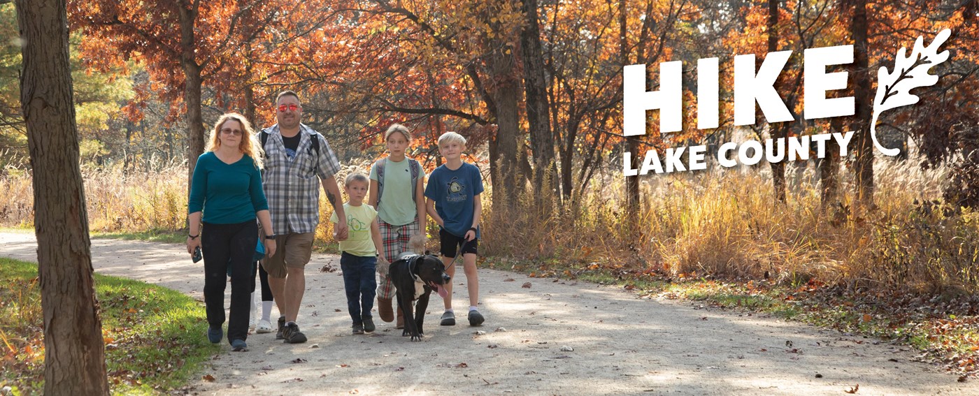 Two adult and three children walking their dog on a path.