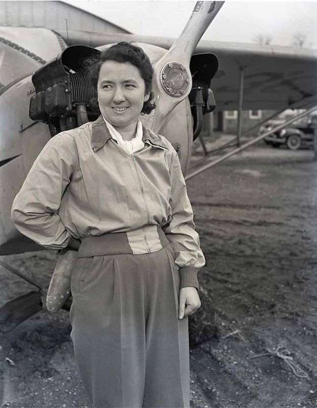 Female pilot in front of World War II airplane.