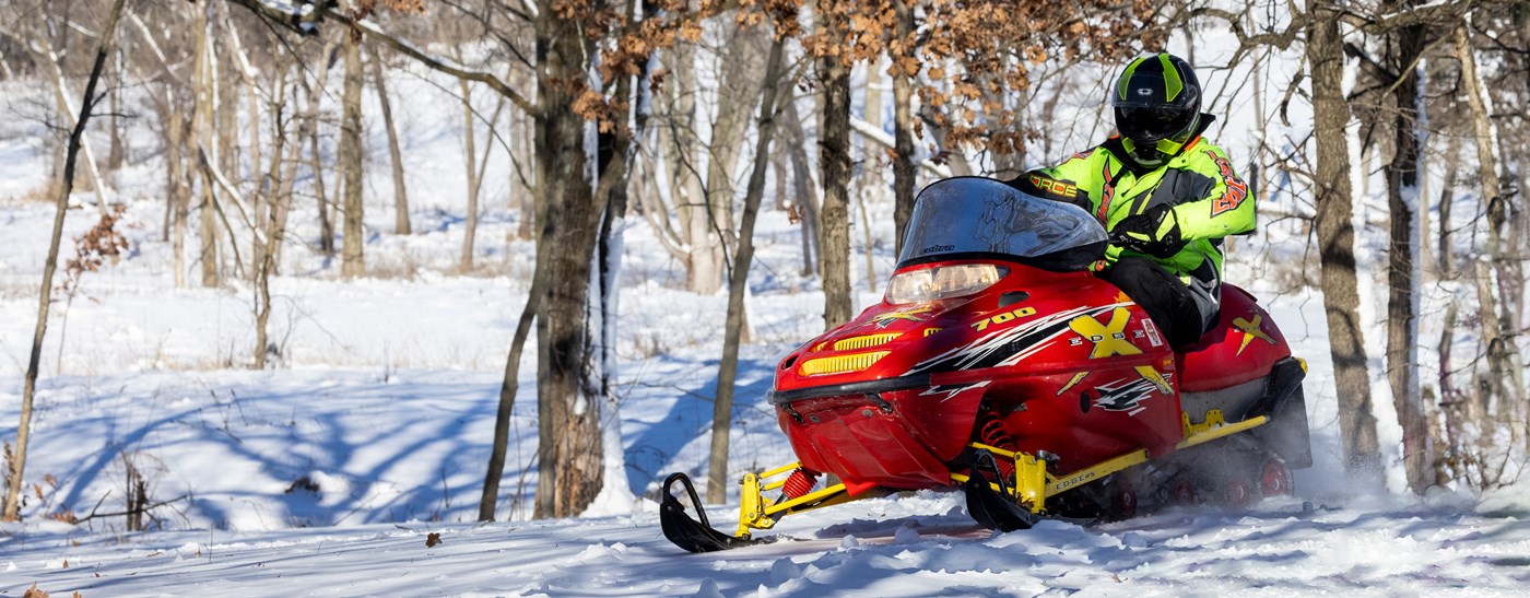 Bright red snowmobile racing through the woods