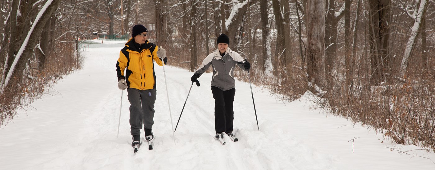 Couple cross skiing through the woods