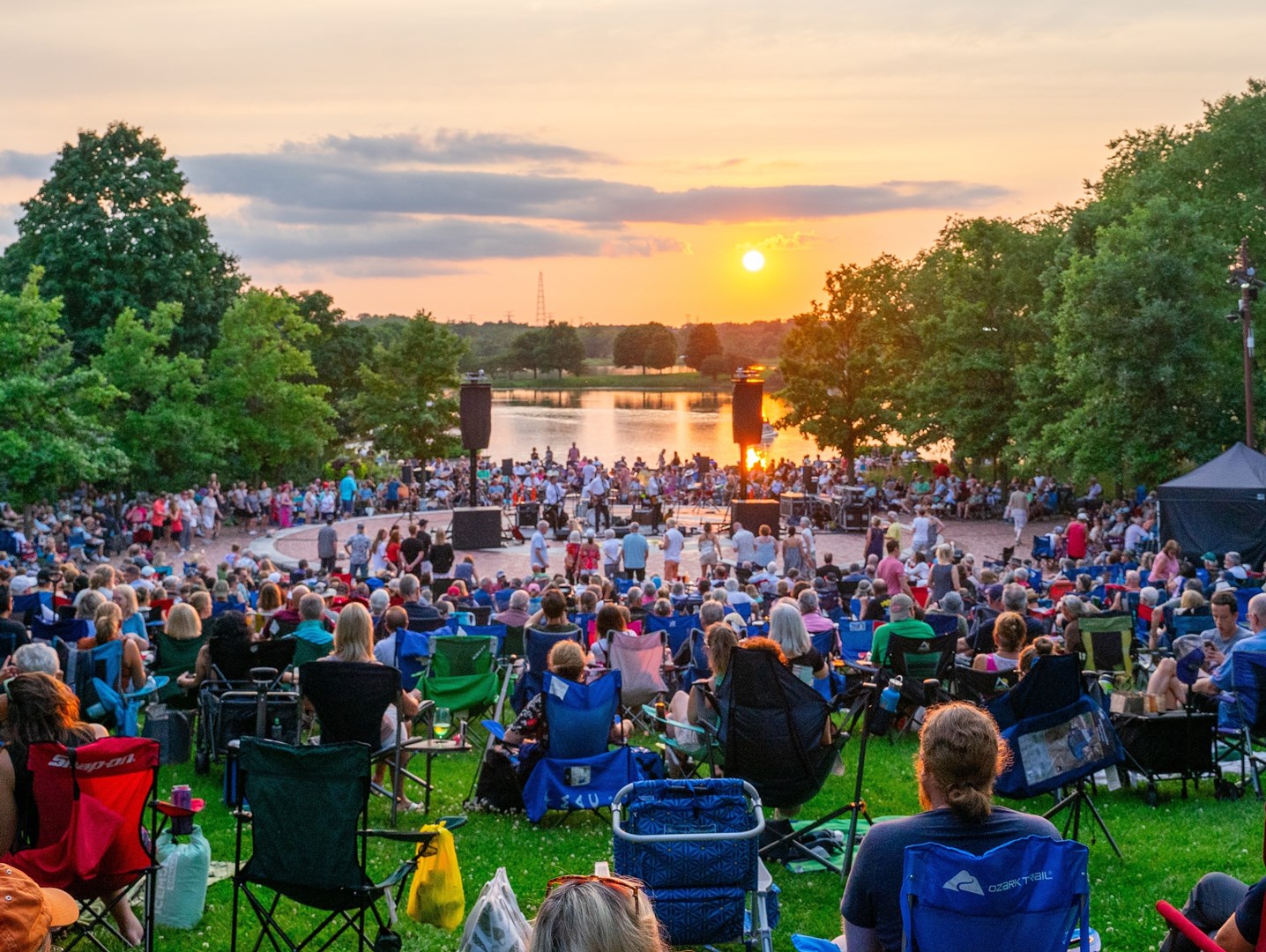 Sunset over a large group of people at an outdoor concert.