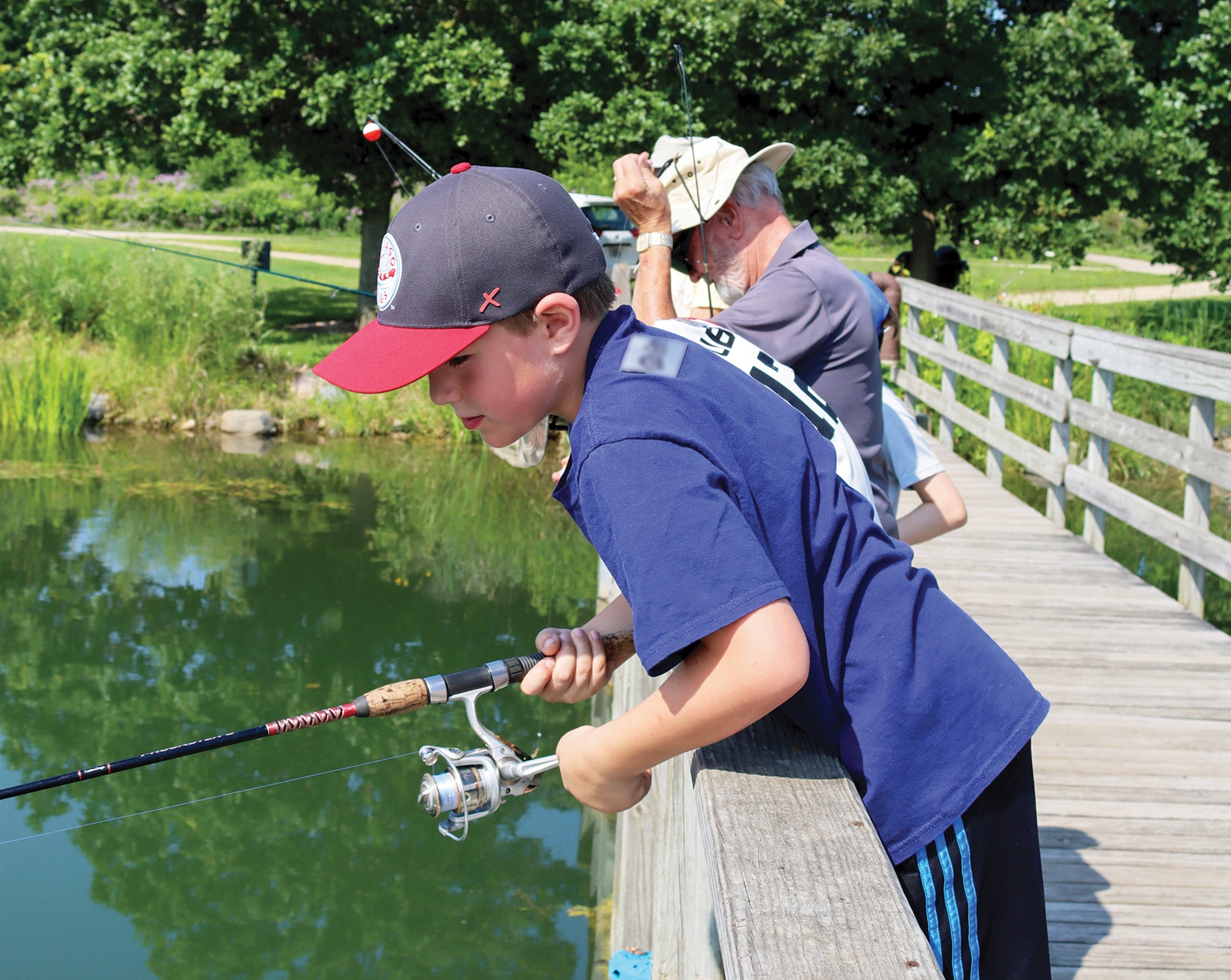 Instructor teaching young children how to fish on a pier.